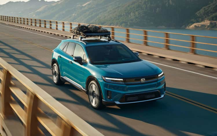 2026 Honda Prologue Elite in North Shore Pearl crossing a bridge in afternoon light, featuring Honda Genuine Accessories.