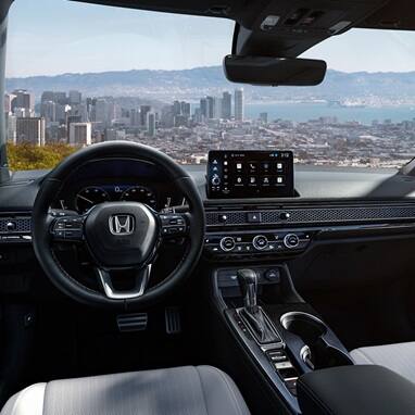 2027 Honda Civic Sedan Sport Touring Hybrid dashboard and front cabin view overlooking a city skyline (Compact Sedan)